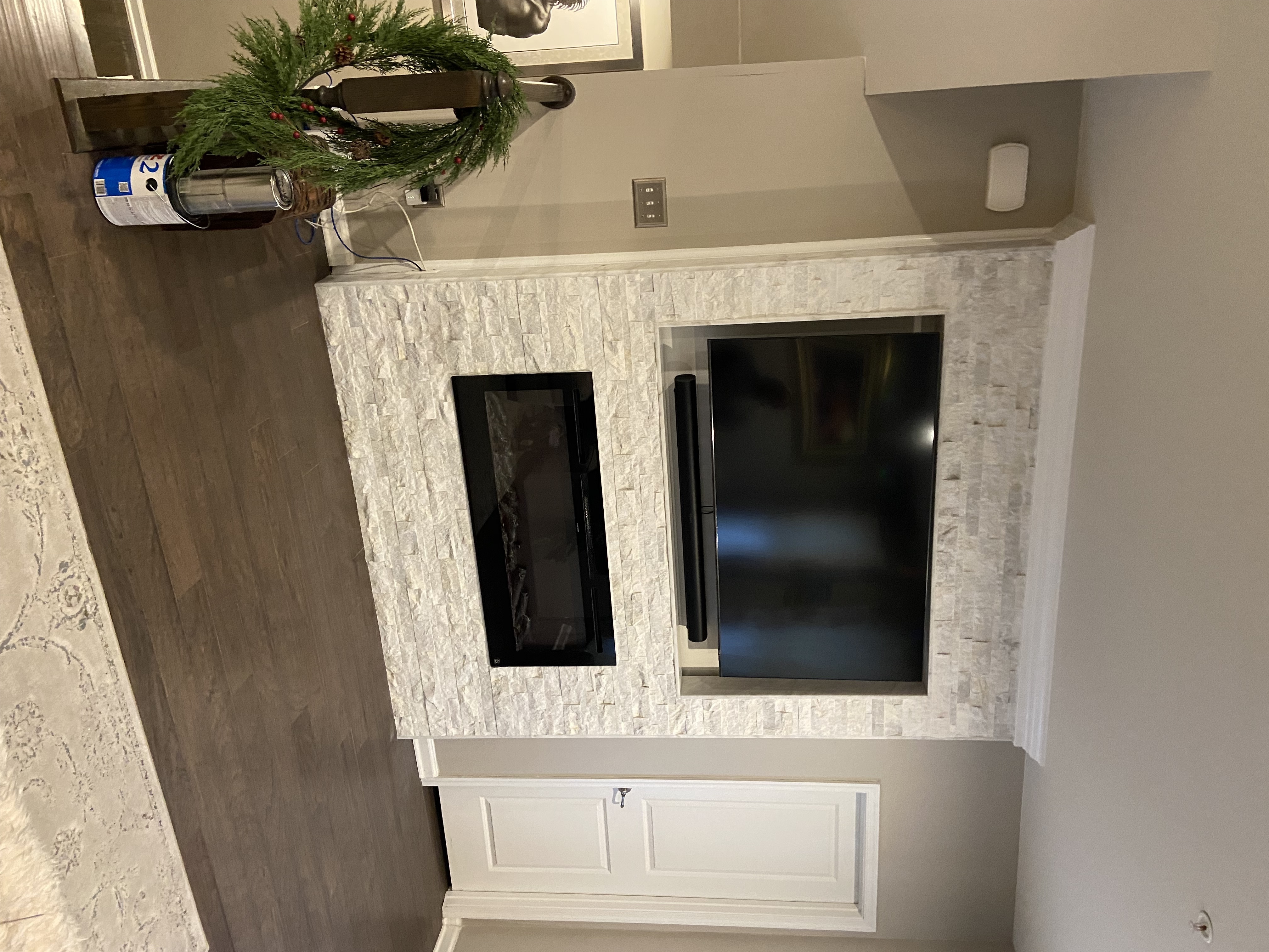 A brand-new accent wall installation from A&N, including fireplace, crown molding, TV, and cracked-stone tile.