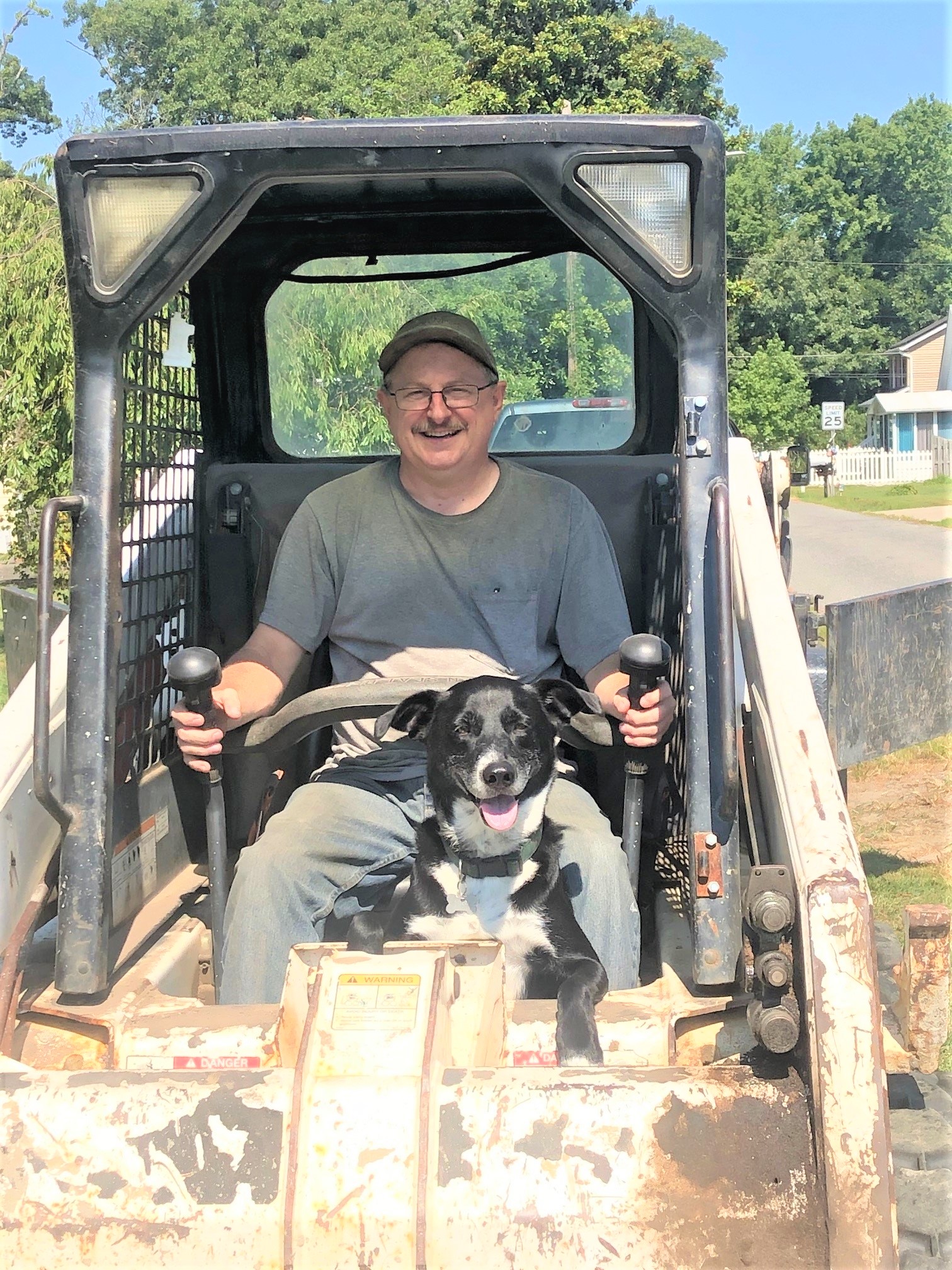 Highlighting the owner of A&N Contracting and his family dog while working on a project using a bobcat skid-steer loader. 